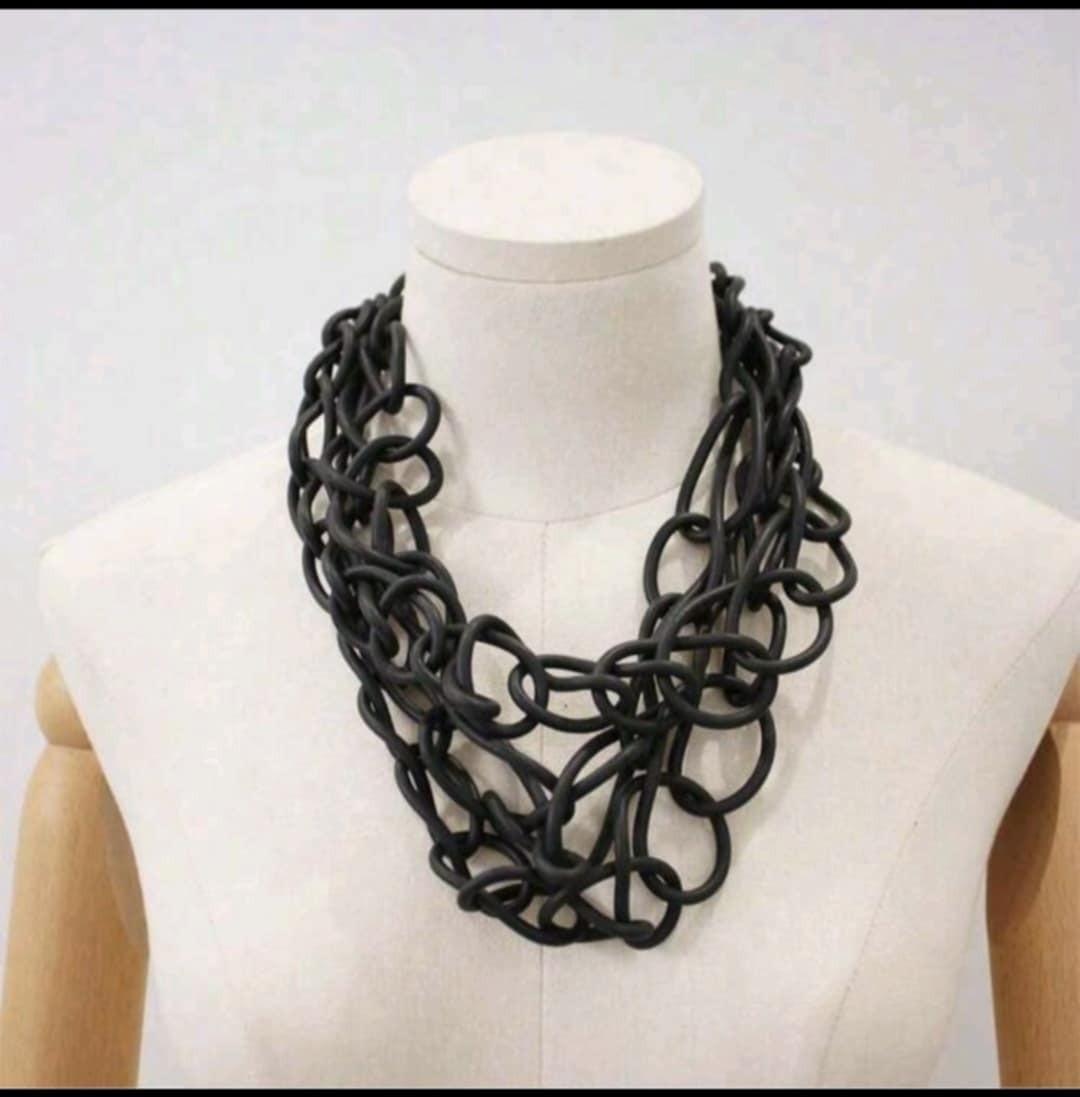 Black chunky rubber statement necklace with multi-strand interlocking chain design displayed on mannequin.