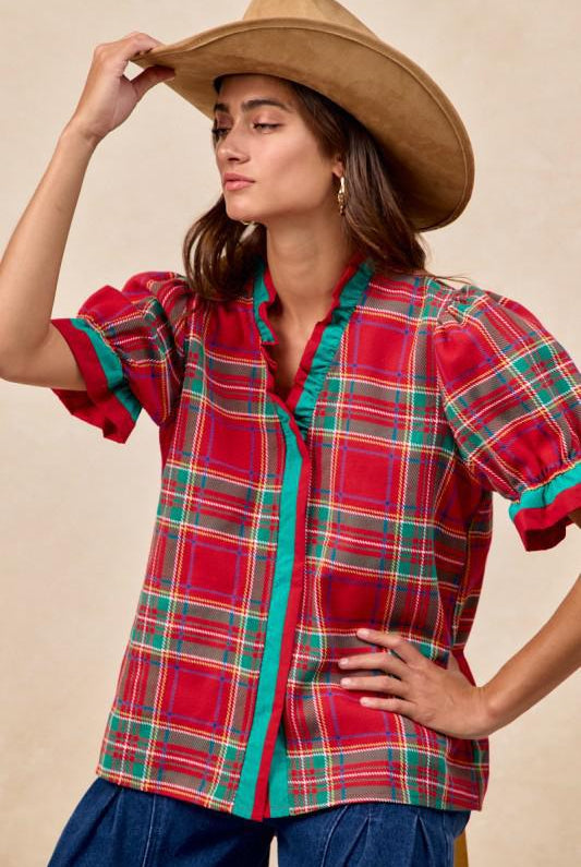 Woman wearing red plaid blouse with green trim and ruffled puff sleeves – festive holiday top by Petunias of Naples