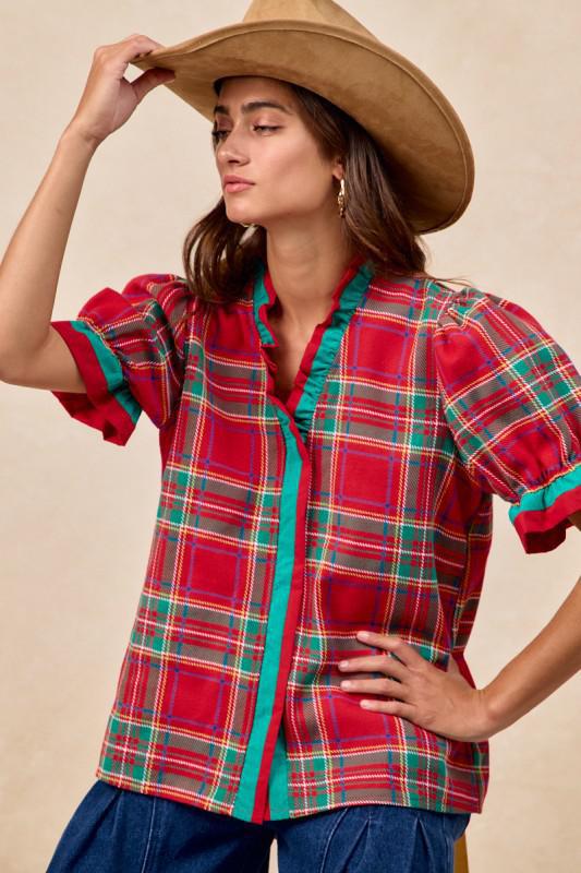 Woman wearing red plaid blouse with green trim and ruffled puff sleeves – festive holiday top by Petunias of Naples
