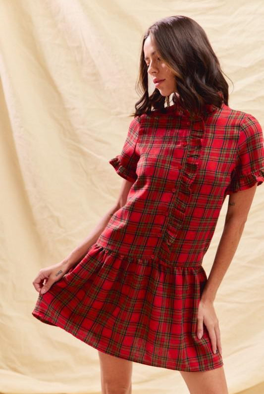 Woman wearing a red plaid dress against a beige background