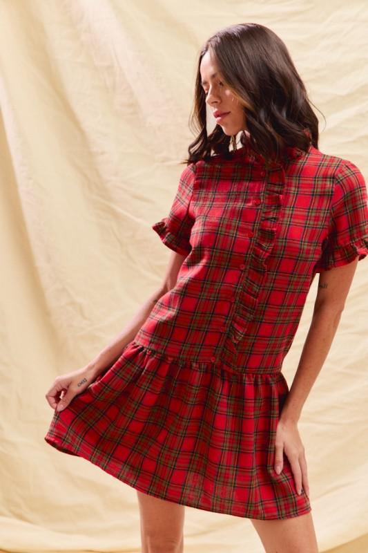 Woman wearing a red plaid dress against a beige background