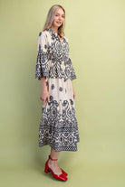 Woman wearing a black and cream patterned dress on a green background