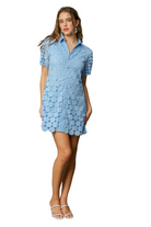 Model wearing light blue shirt dress with circular appliqué detailing and short sleeves, styled with white sandals.