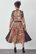Chic urban woman wearing snakeskin print and black contrast midi dress with pleated skirt and flowing panels, Back View