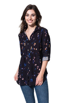 A woman wearing a black blouse with a pleated bust and tabbed sleeves, featuring a button front. She is also wearing blue jeans.