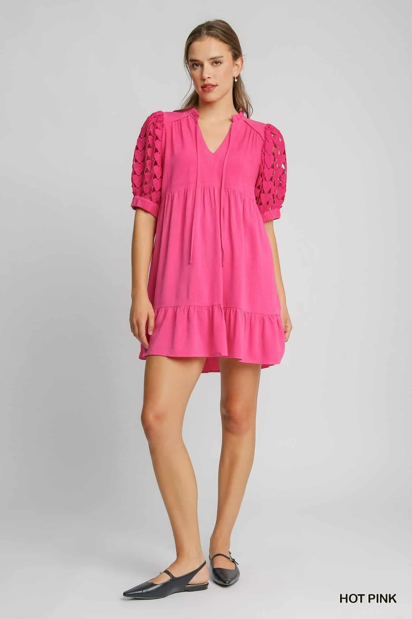 Woman wearing a pink dress with puff sleeves on a gray background