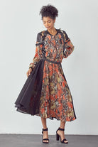 Chic urban woman wearing snakeskin print and black contrast midi dress with pleated skirt and flowing panels