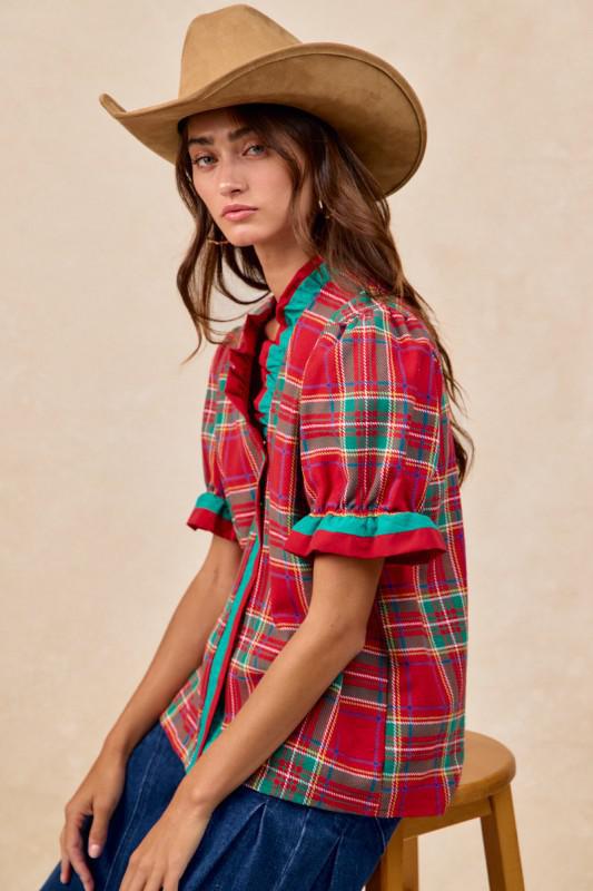Woman wearing red plaid blouse with green trim and ruffled puff sleeves – festive holiday top by Petunias of Naples