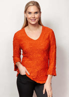 Model wearing Sno Skins Dreamcatcher Crinkle Tunic in vibrant orange with 3/4 sleeves, made in the USA – boutique fashion from Petunias of Naples.