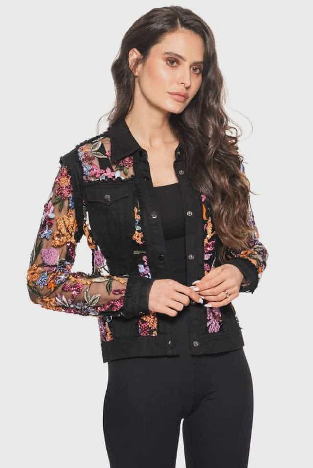 Woman wearing a black denim jacket with floral  sequins and embroidery on a white background