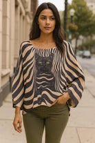 Beautiful urban chic woman wearing a Made in Italy dolman sleeve zebra stripe sweater with cat design, styled with khaki green pant