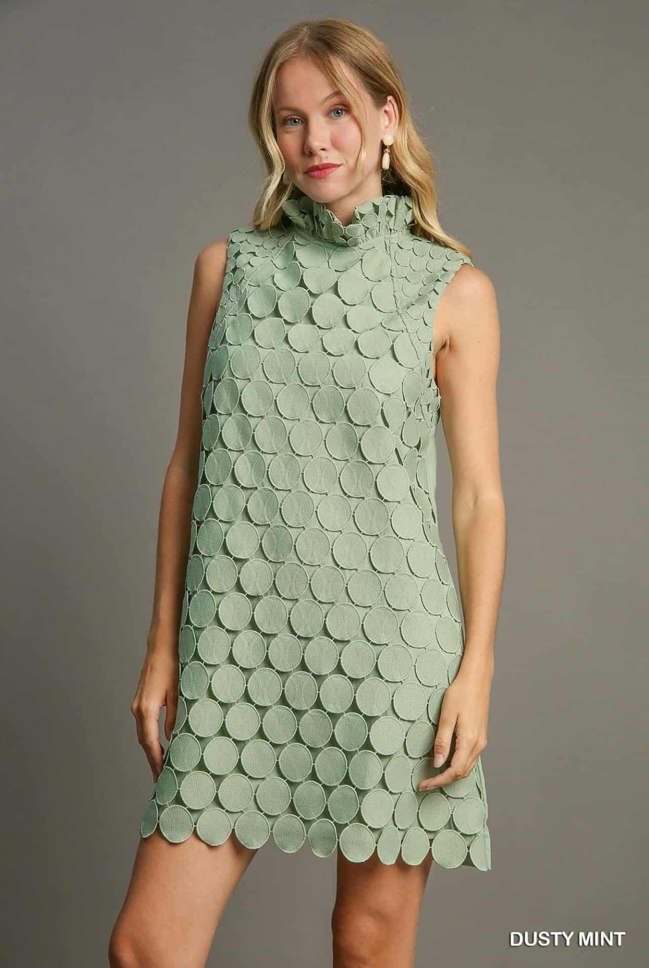 Close-up of ruffled mock neck and textured circular detailing on dusty mint dress.