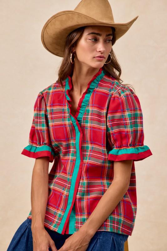 Woman wearing red plaid blouse with green trim and ruffled puff sleeves – festive holiday top by Petunias of Naples