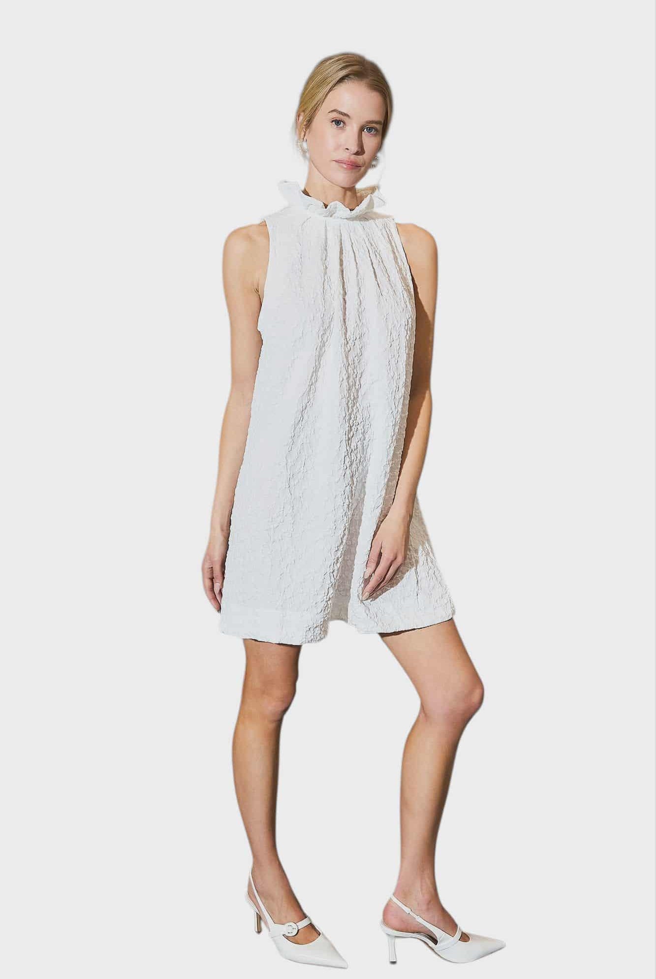 Woman wearing a white sleeveless dress with a high neckline on a white background