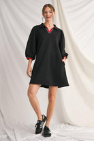 Black shift dress with red and green trim at neckline and cuffs