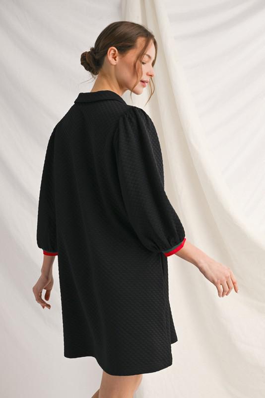 Back View of Woman wearing a black dress with red trim against a white background