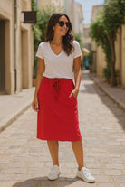 . Travel chic outfit idea featuring red knit skirt styled with white tee and sneakers