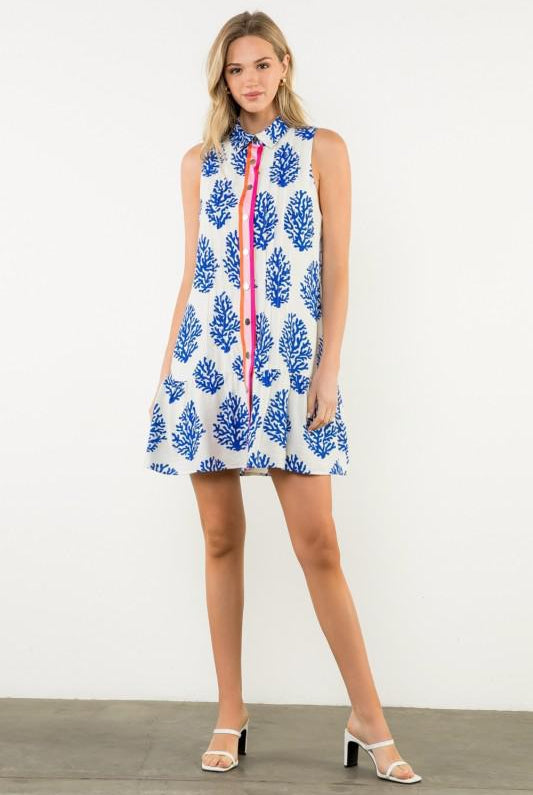 Woman wearing a sleeveless dress with blue floral pattern on a white background