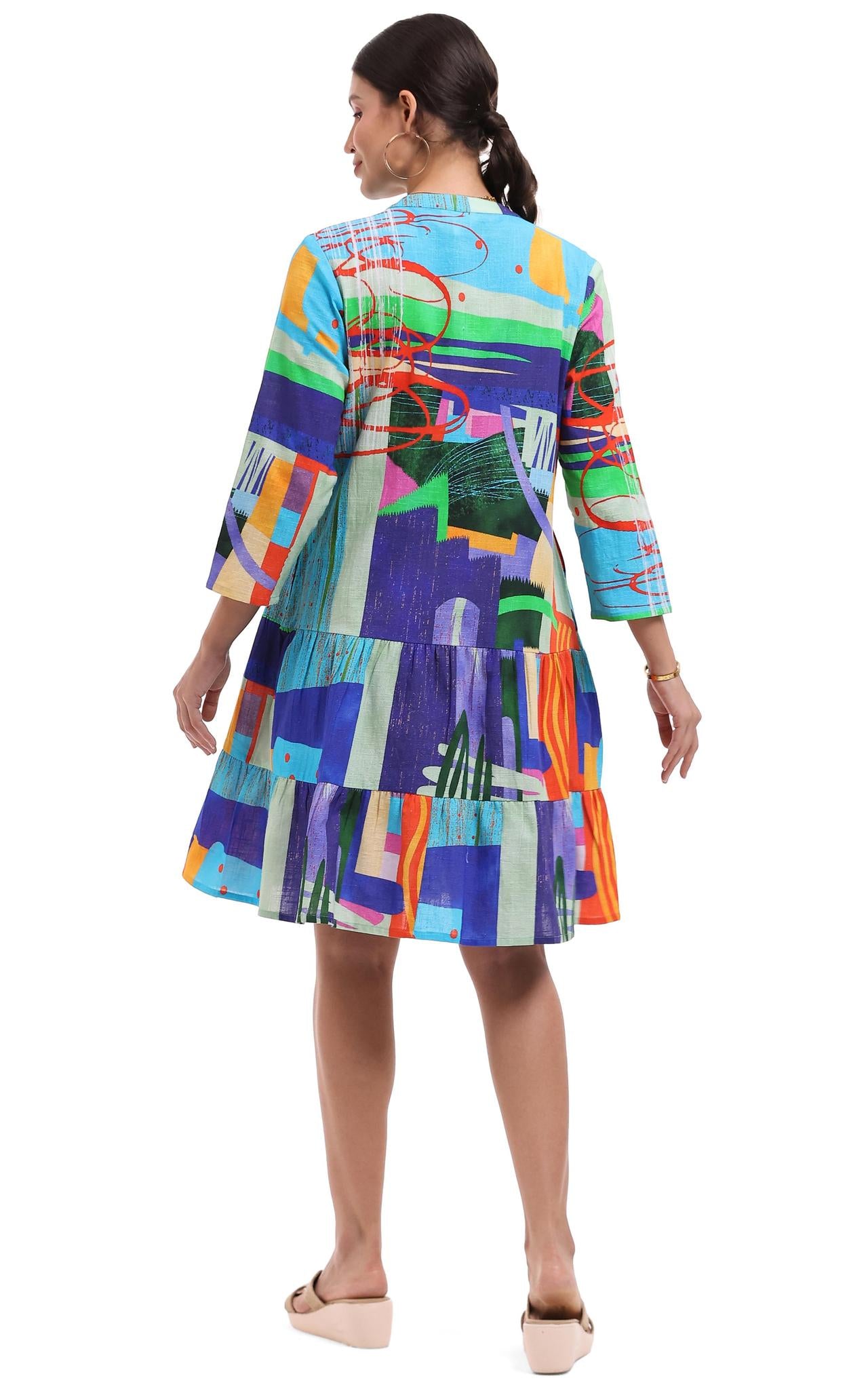 Woman wearing a colorful Parsley & Sage 100% cotton tiered dress with abstract patchwork print back View