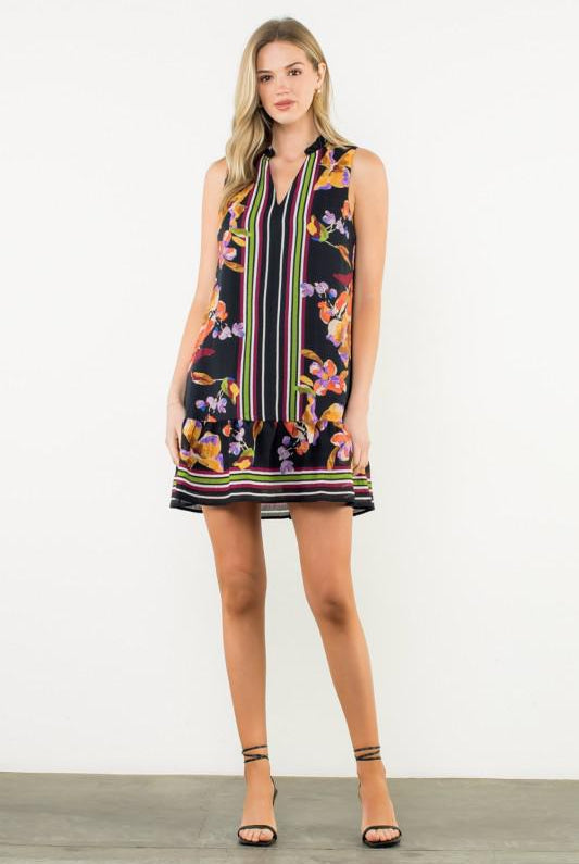 Woman wearing a sleeveless dress with floral and striped pattern on a white background