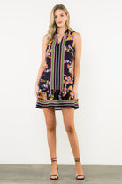 Woman wearing a sleeveless dress with floral and striped pattern on a white background