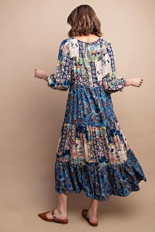 Woman wearing a long, patterned dress against a beige background