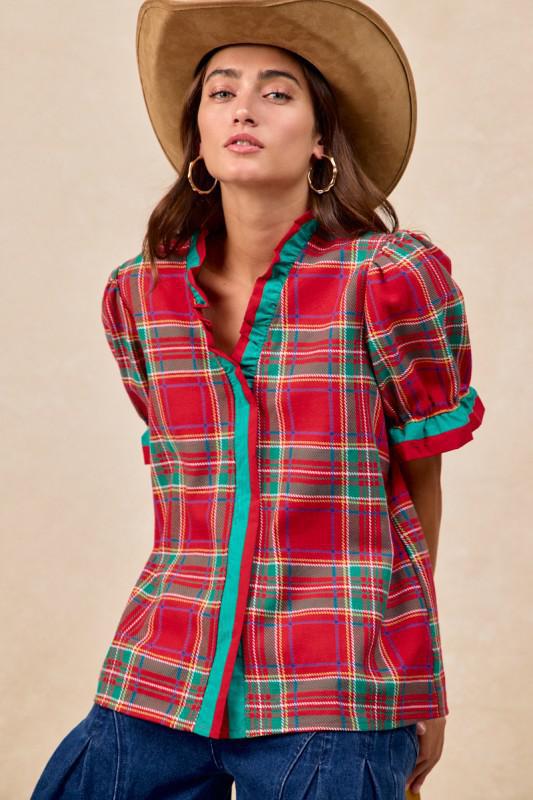 Woman wearing red plaid blouse with green trim and ruffled puff sleeves – festive holiday top by Petunias of Naples