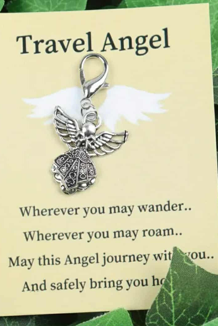Silver angel charm on a 'Travel Angel' card with green leaves in the background