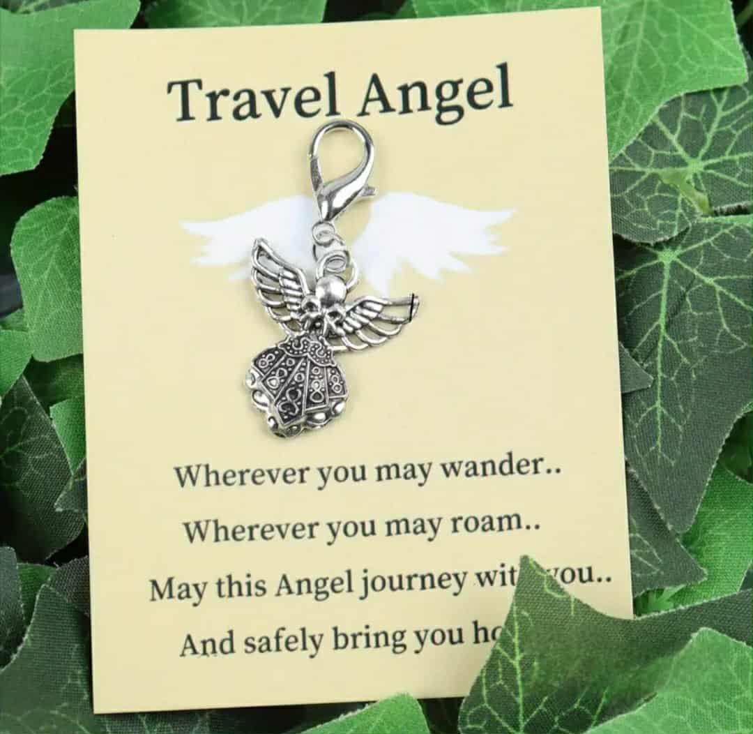 Silver angel charm on a 'Travel Angel' card with green leaves in the background