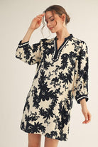 Model wearing Jodifl black and cream floral tunic dress with scalloped trim neckline and ¾ sleeves, photographed against white background— Petunias of Naples