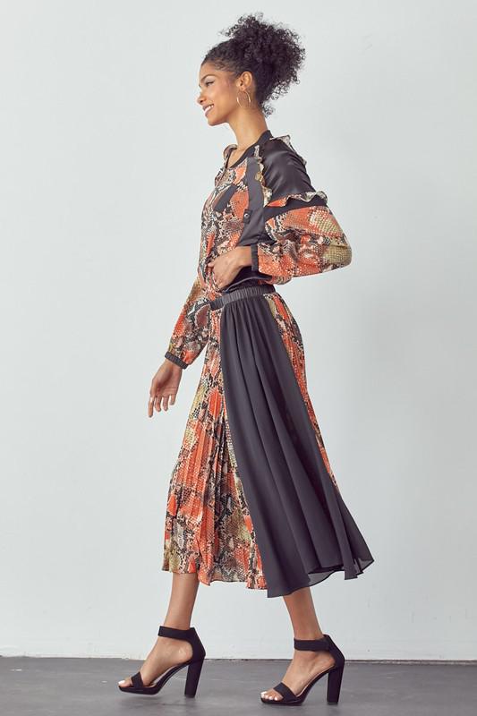 Woman wearing a patterned dress with a black skirt against a white background