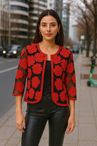 Woman wearing Parsley & Sage red floral embroidered sheer jacket over black top with leather pants