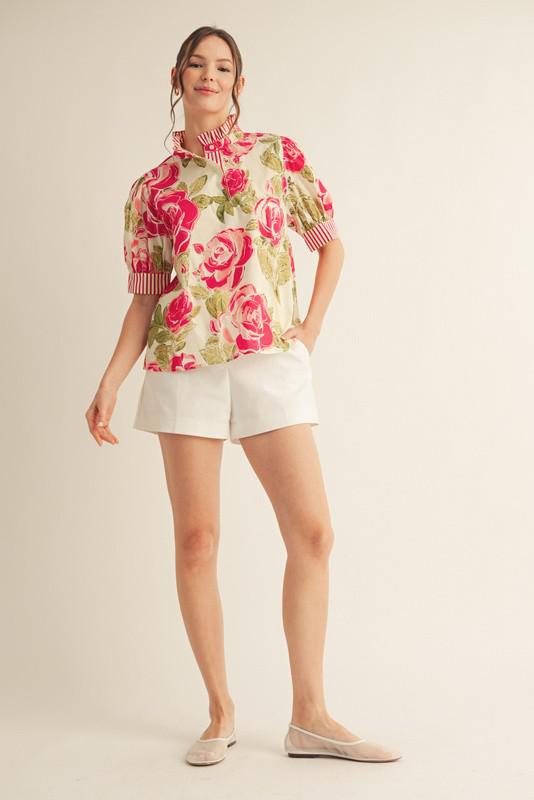 Woman wearing a floral blouse and white shorts on a beige background