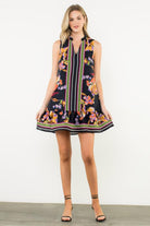 Woman wearing sleeveless floral stripe shift dress with ruffle hem