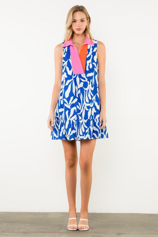 Front view of sleeveless blue and white print dress with pink collar and ruffled hem.