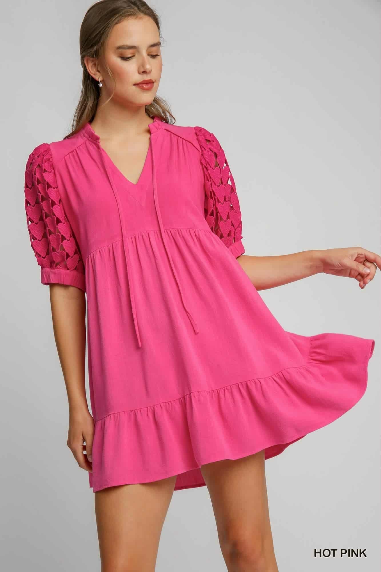 Woman wearing a hot pink dress with lace sleeves on a gray background