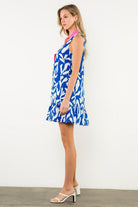 Model wearing blue and white abstract print dress styled with sandals. side view