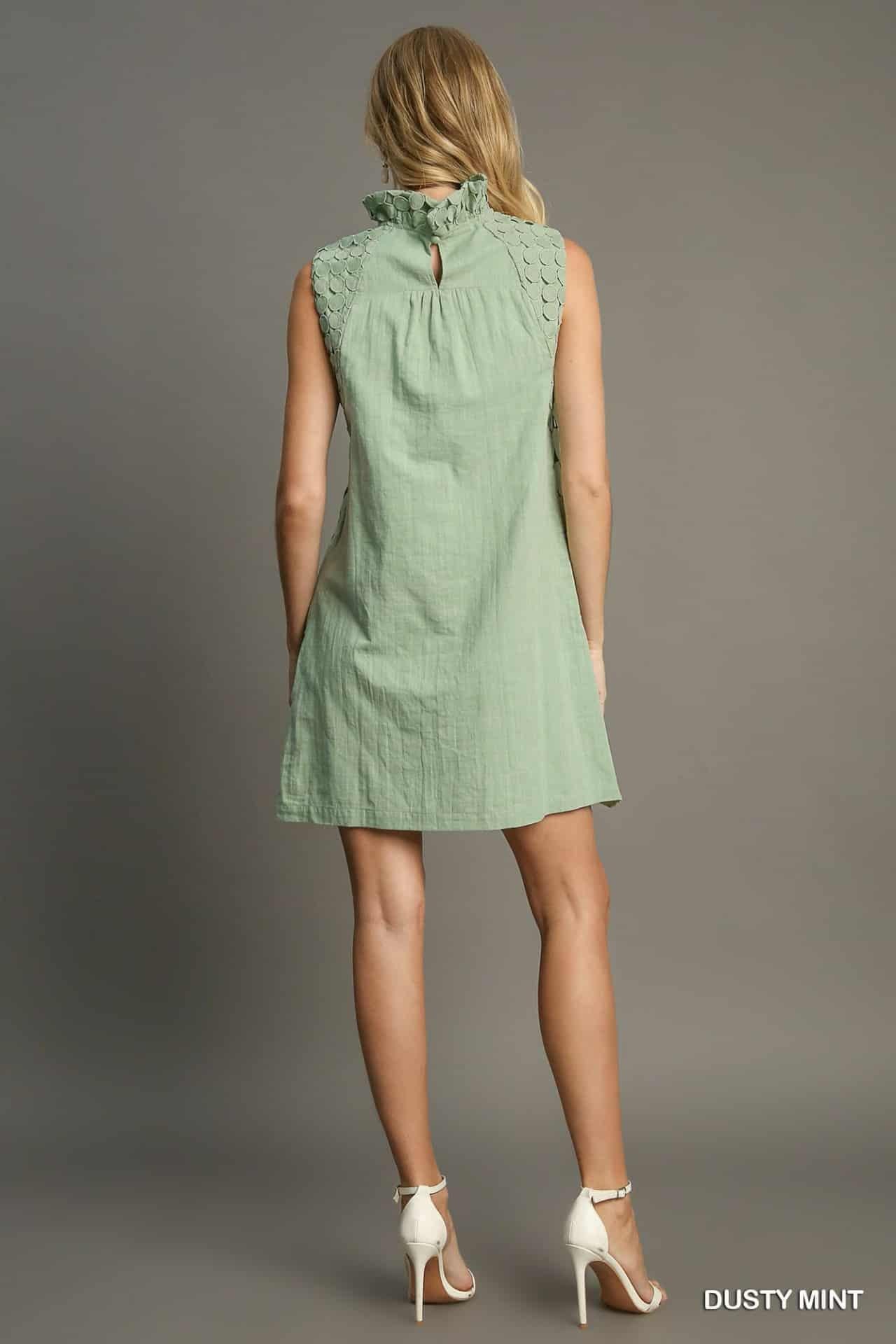 Woman wearing a green dress against a gray background, back view