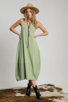 Woman wearing light sage sleeveless midi dress, relaxed fit