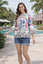 Woman wearing a floral blouse and denim shorts in a tropical setting