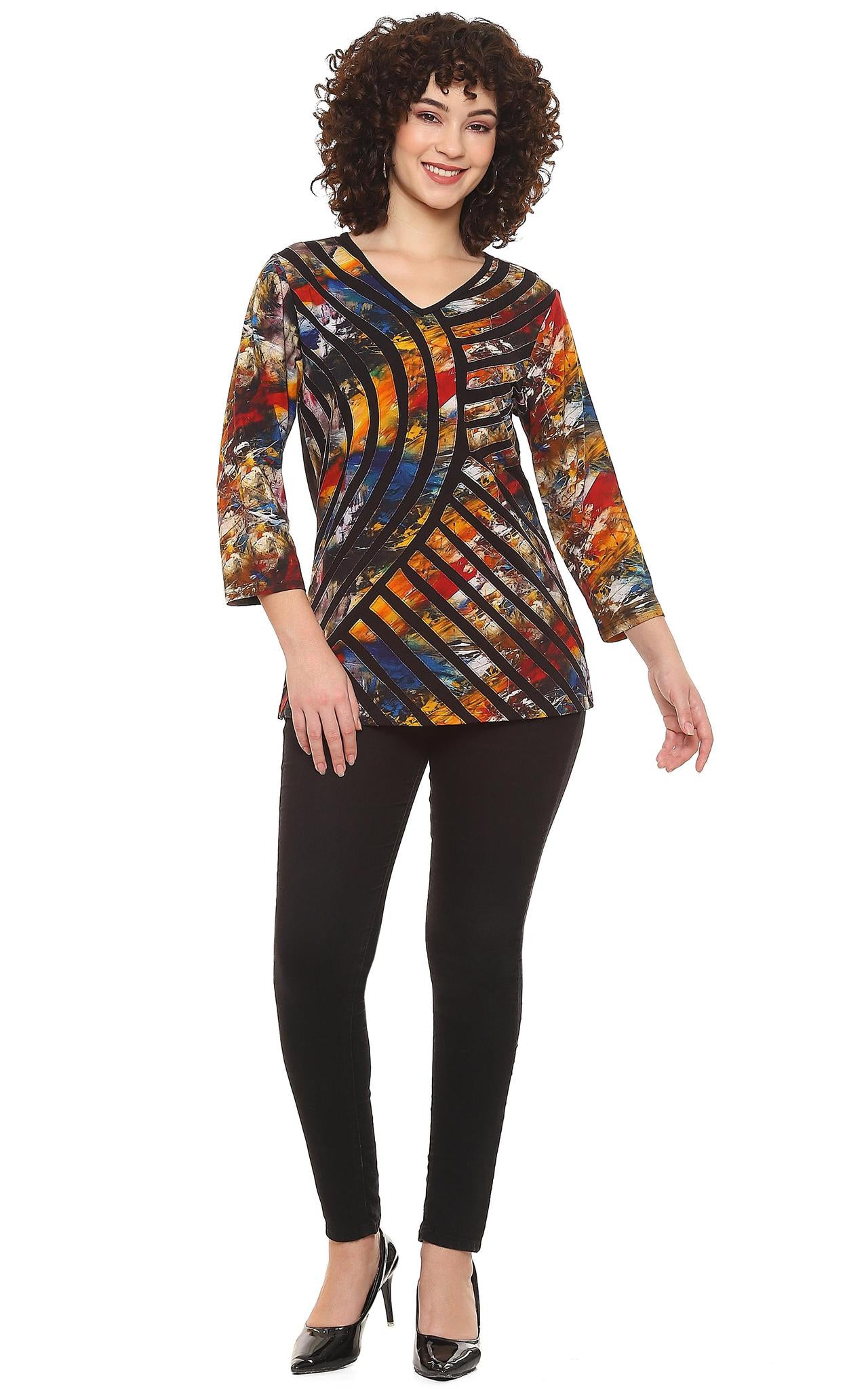 Woman wearing a Parsley & Sage multi-color abstract print V-neck tunic with black geometric stripe design and 3/4 sleeves, paired with black pants.