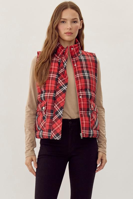 Woman wearing a red plaid puffer vest over a beige shirt on a white background