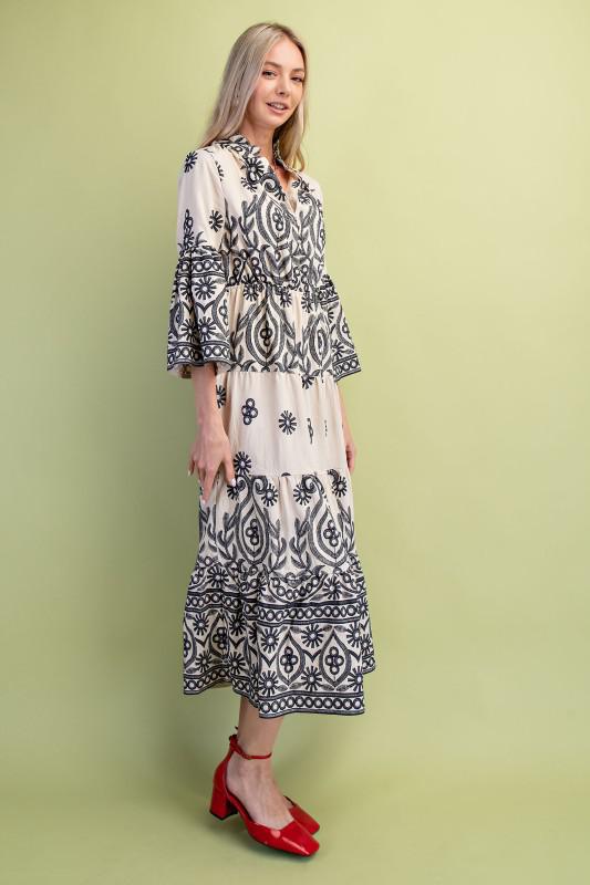 Woman wearing a black and cream patterned dress on a green background