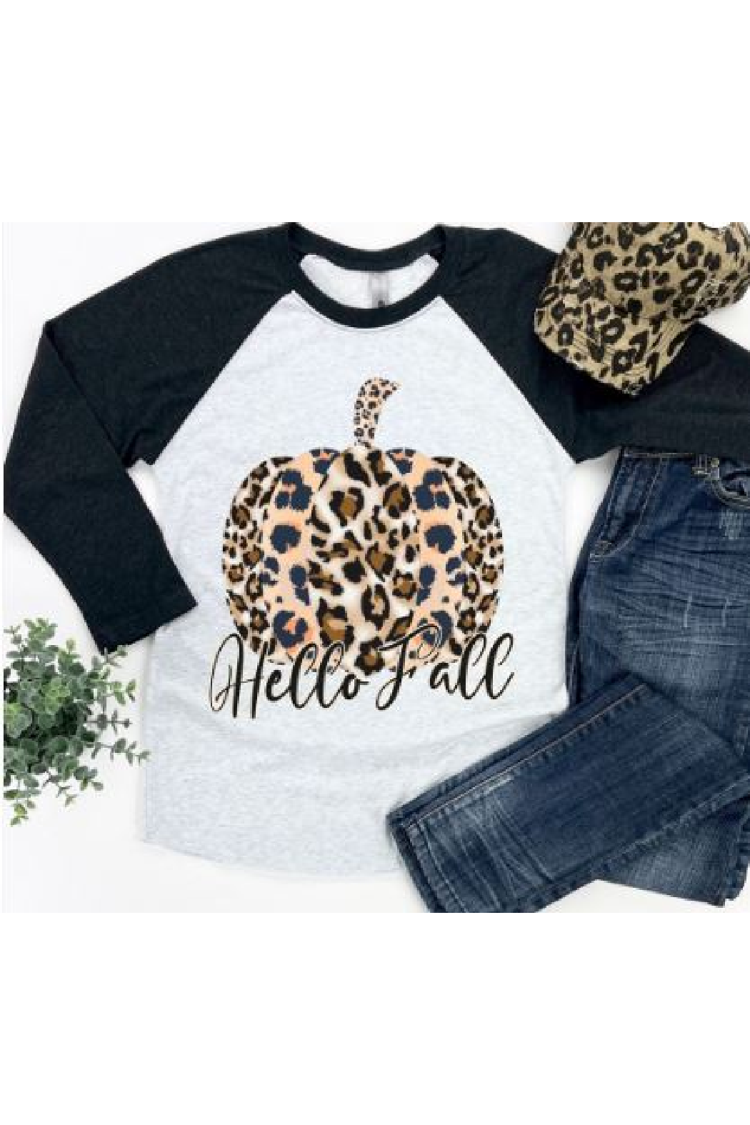A gray t-shirt with leopard print pumpkin graphic and the text 'Hello Fall' on the front, accompanied by blue jeans and a decorative hat.