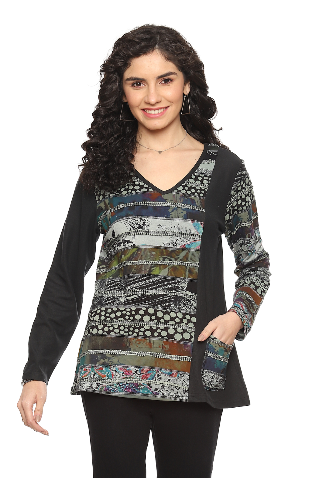 Woman wearing a Parsley & Sage V-neck knit top with artistic patchwork print, long sleeves, and front pocket in earthy tones.