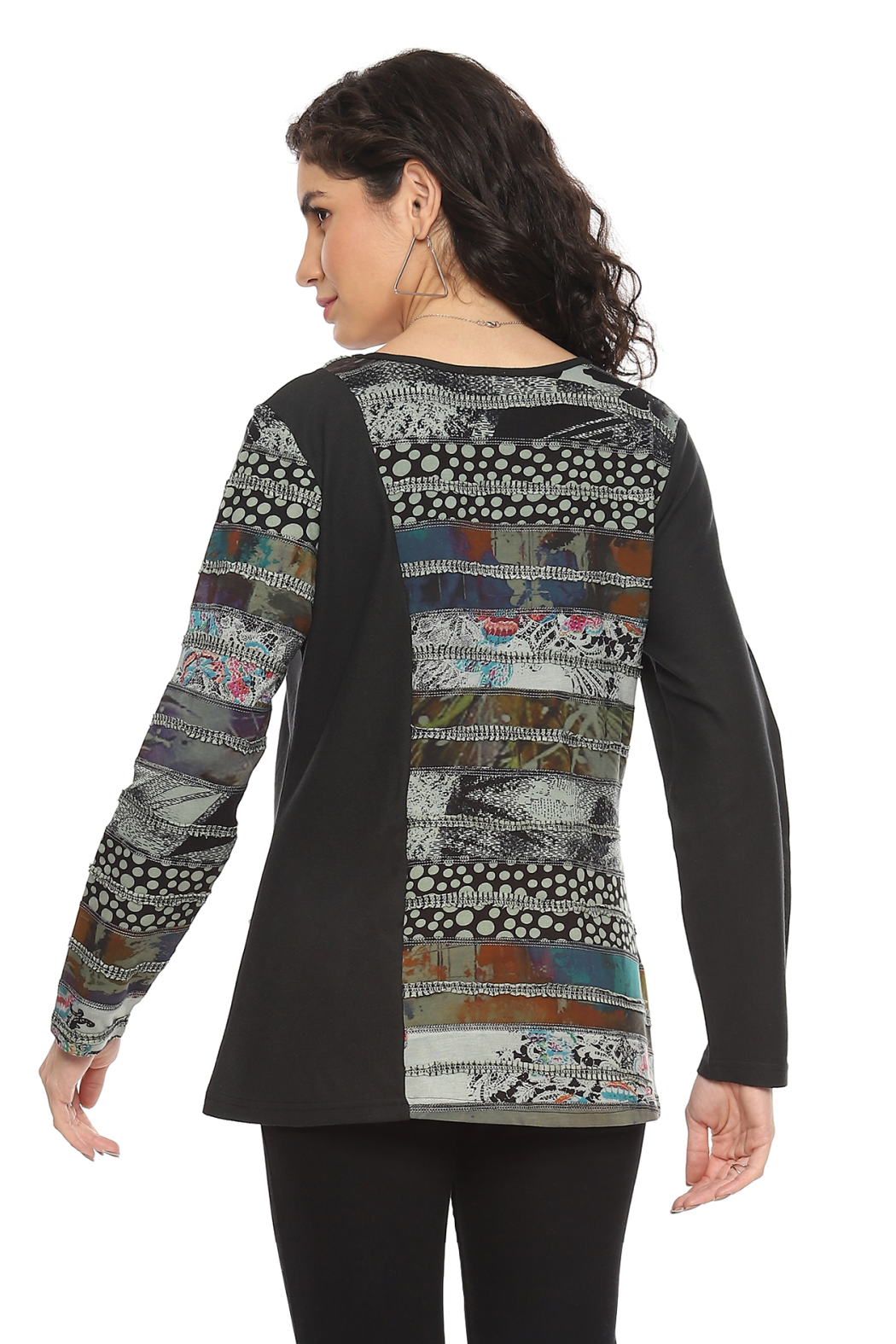 Woman wearing a Parsley & Sage V-neck knit top with artistic patchwork print, long sleeves, and front pocket in earthy tones.