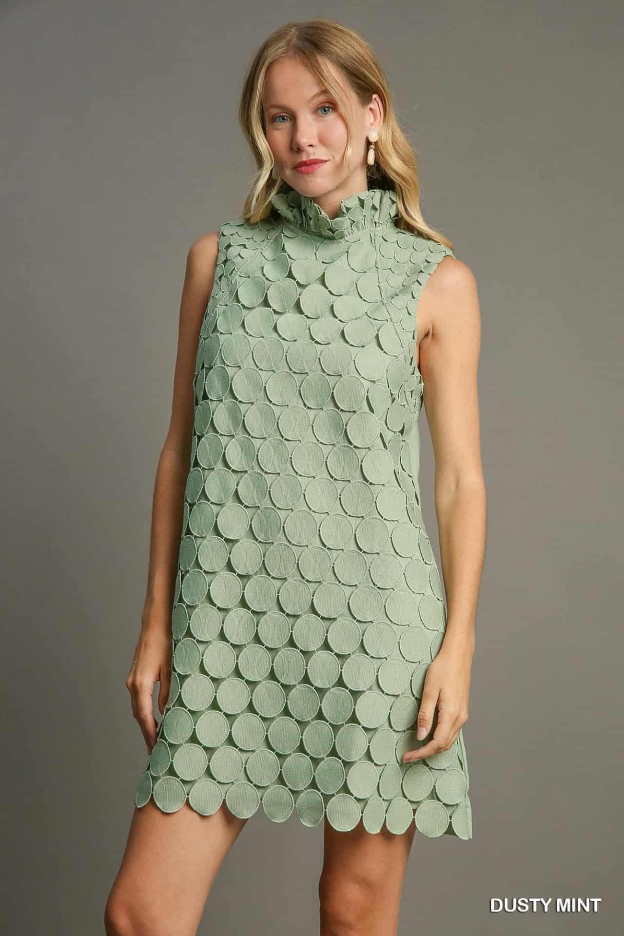 Close-up of ruffled mock neck and textured circular detailing on dusty mint dress.
