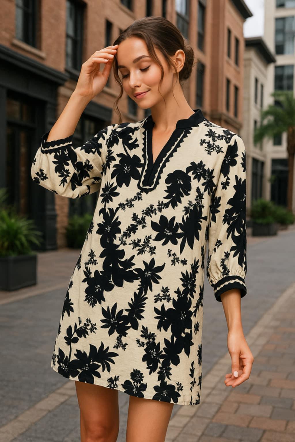 Model wearing Jodifl black and cream floral tunic dress with scalloped trim neckline and ¾ sleeves, photographed in an urban chic setting — Petunias of Naples