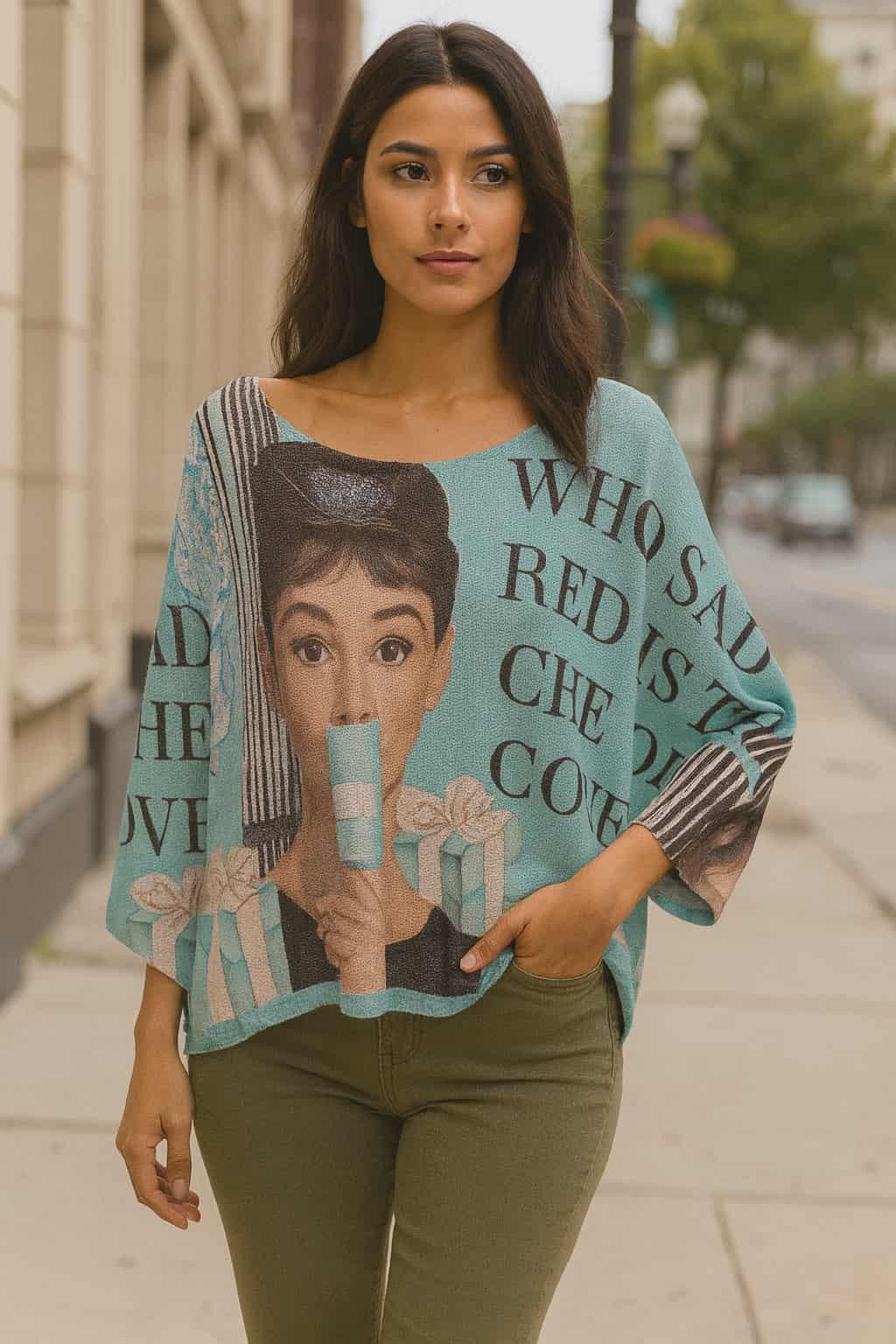 Urban chic woman wearing a lightweight dolman sleeve sweater with Audrey Motif, made in Italy, styled with slim black pants in a city street setting.