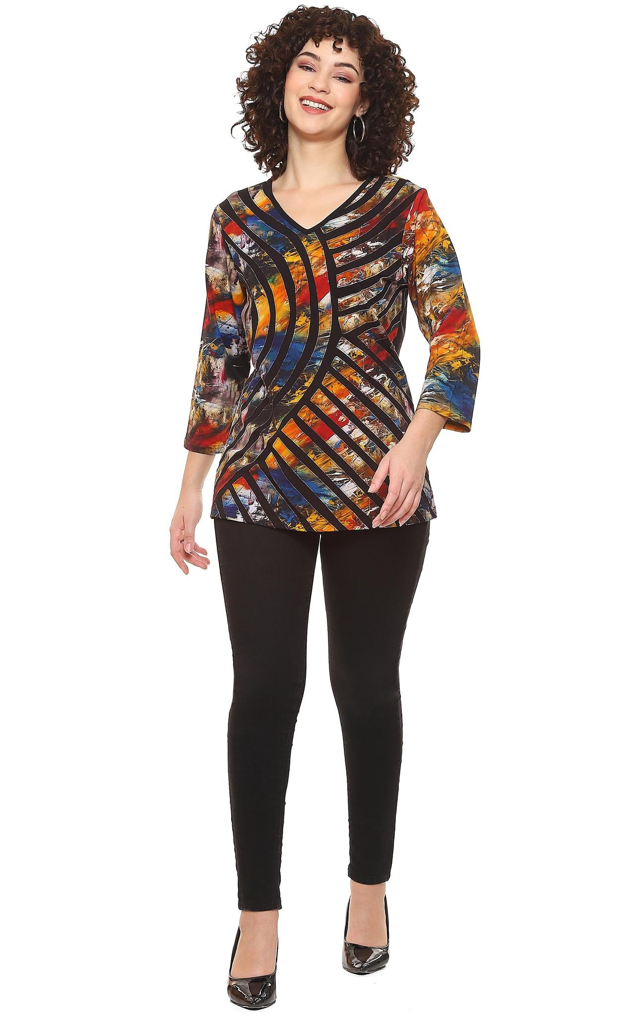 Woman wearing a Parsley & Sage multi-color abstract print V-neck tunic with black geometric stripe design and 3/4 sleeves, paired with black pants.